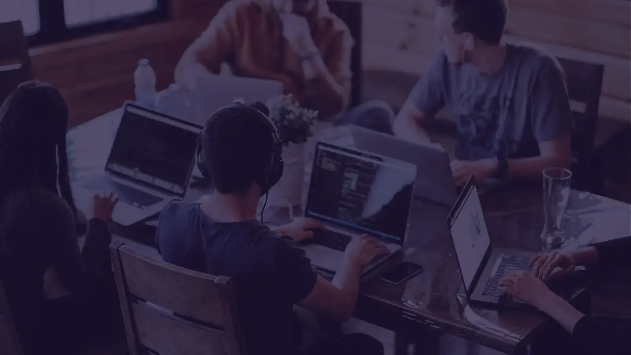 Group of people working on laptops in a collaborative office setting