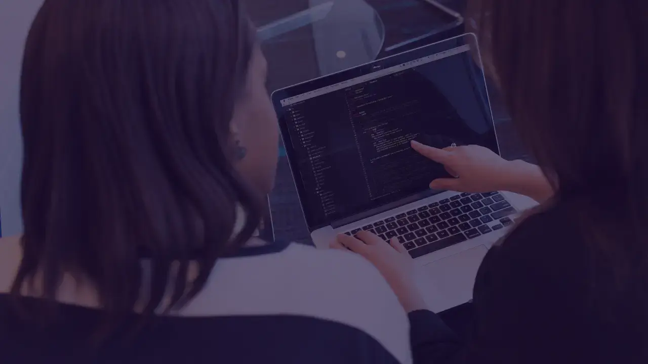 Two women collaborating on coding project on a laptop