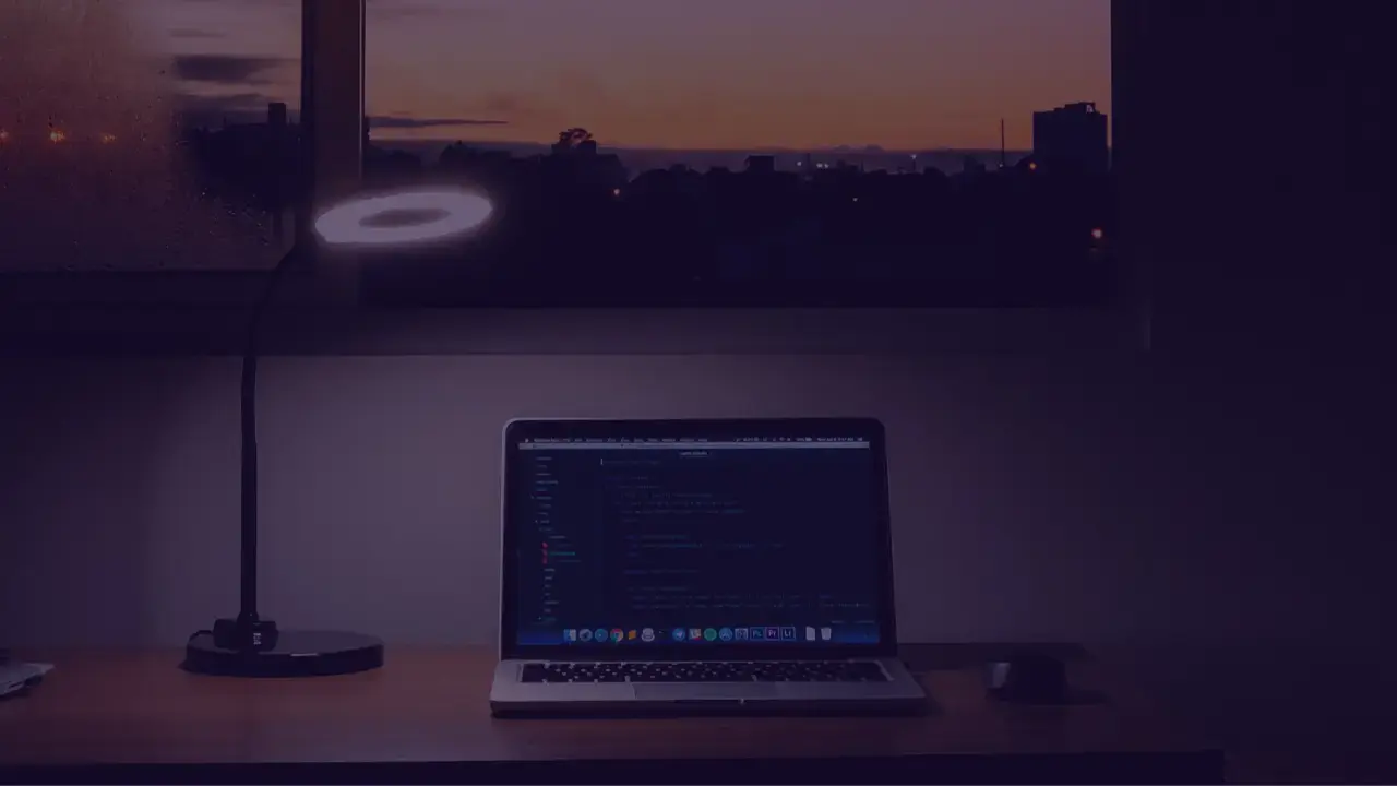 computer on a desk by a window with a beautiful sunset