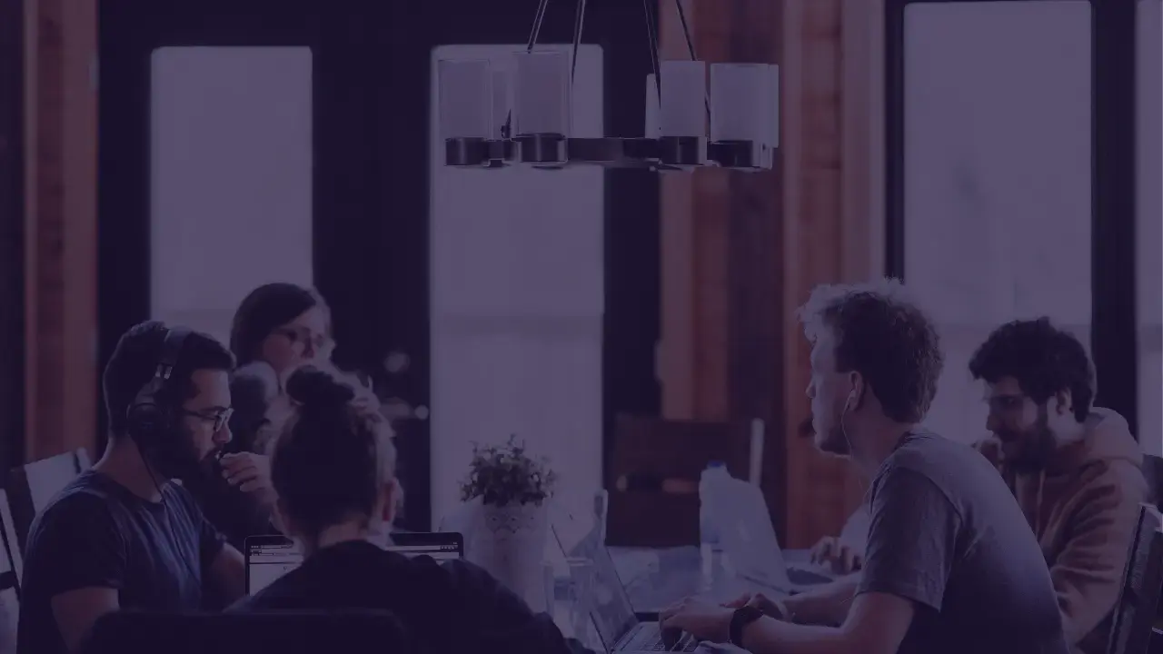 picture of a group of people working on laptops and talking around a table