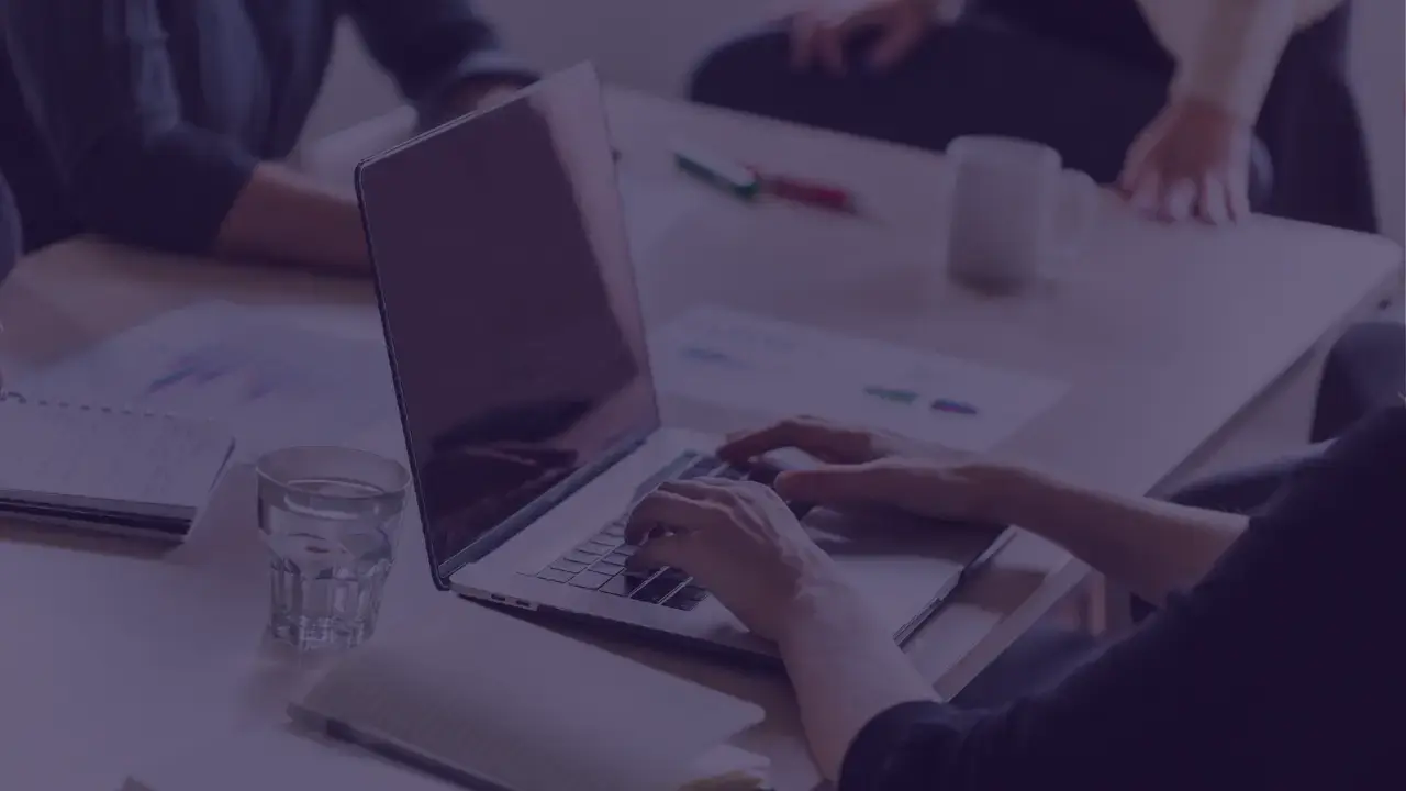 person working on laptop at a table with other people there