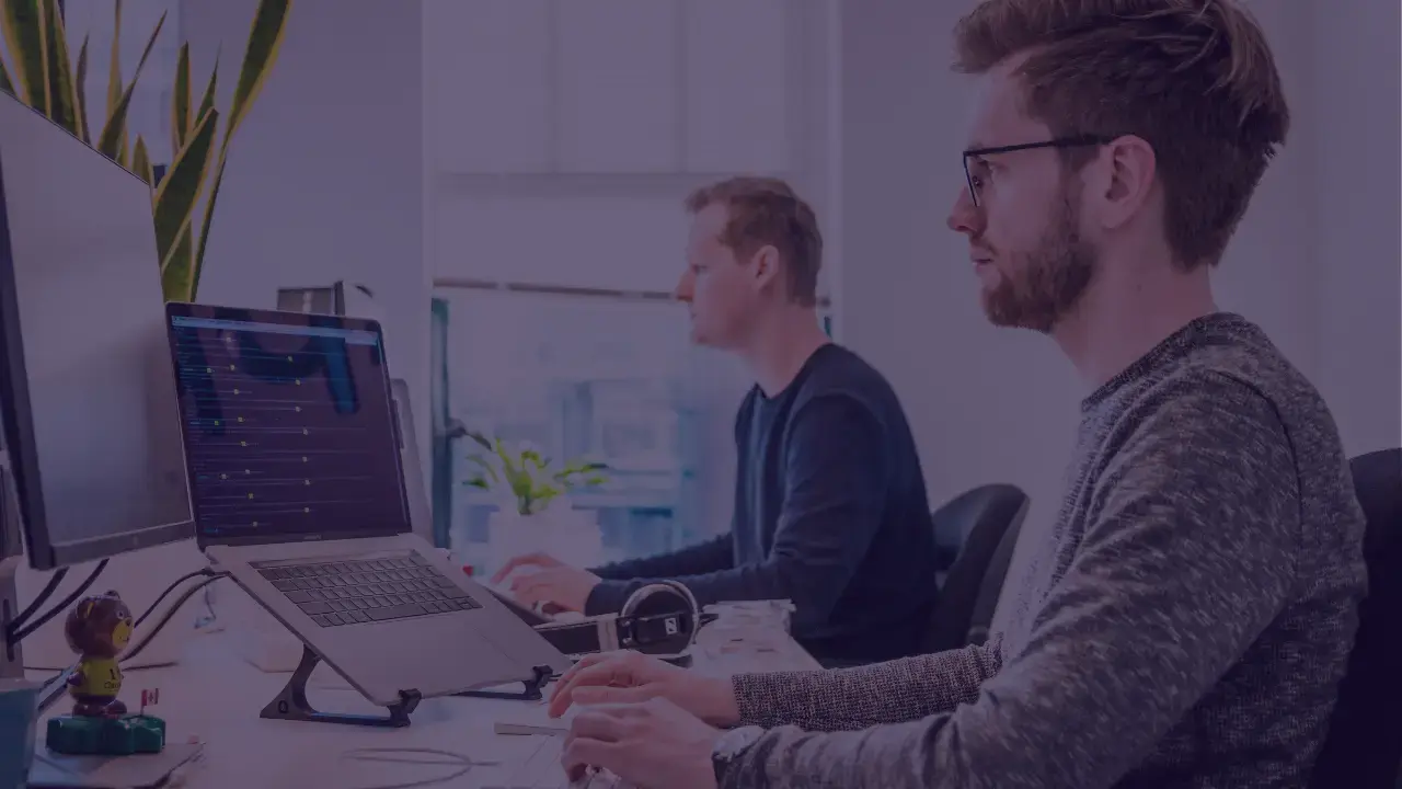 two men sit next to each other working on computers